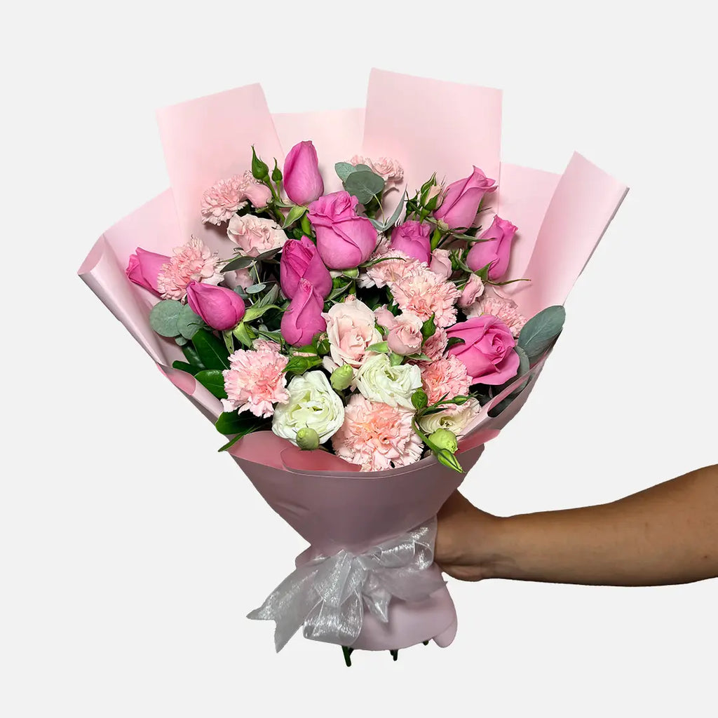 Ramo de 12 rosas rosas, clavel rosa, mini rose rosa y follaje. Envuelto en papel coreano rosa.