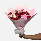 Ramo de 24 rosas en color rojo y rosa con follaje, envueltas en papel coreano rosa y moño blanco.